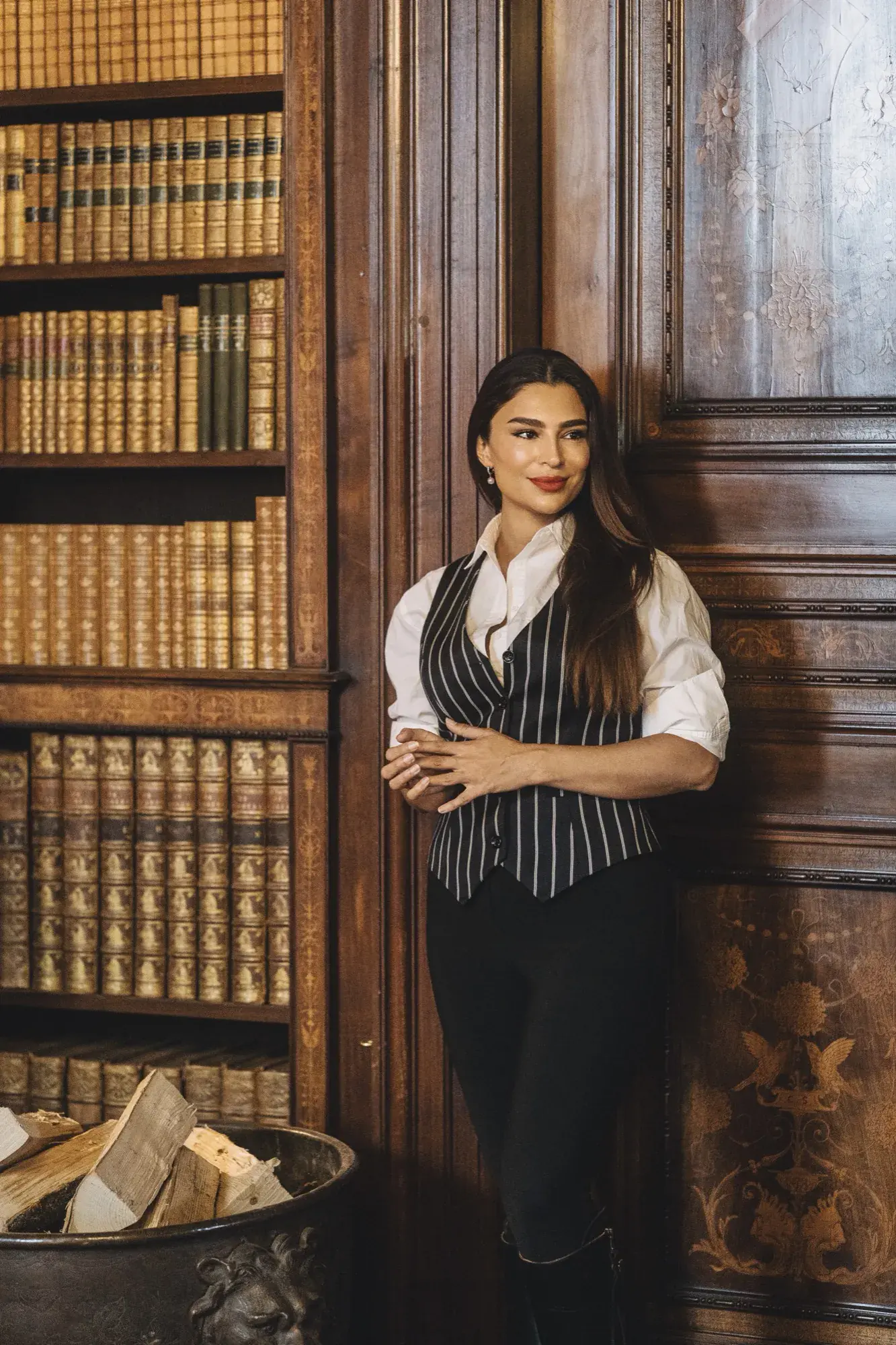 Handan Darici leaning against the panelled shelves of a manor library